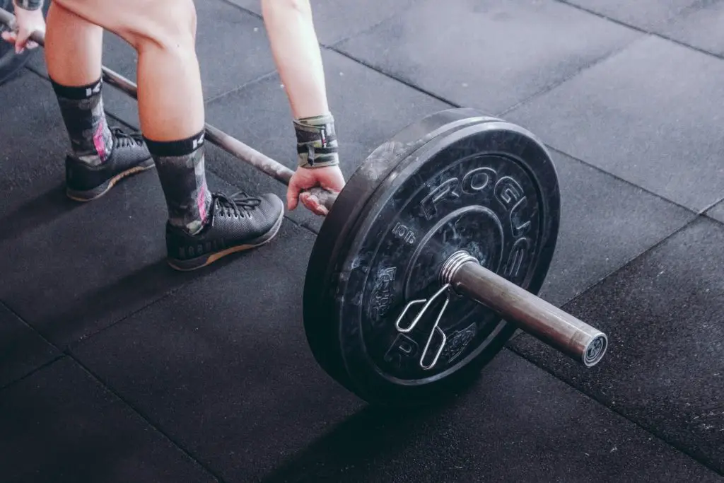 close-up view of person picking up weight bar for a deadlift