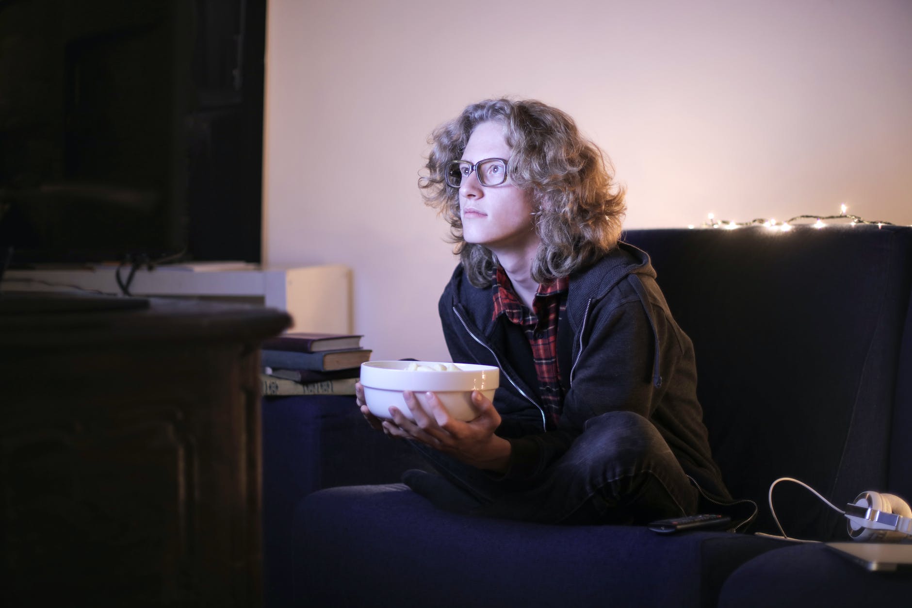 man with a bowl of popcorn watching tv at home