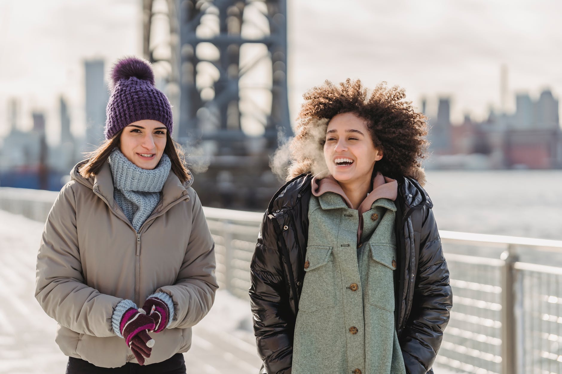 happy multiethnic women walking on bridge in city