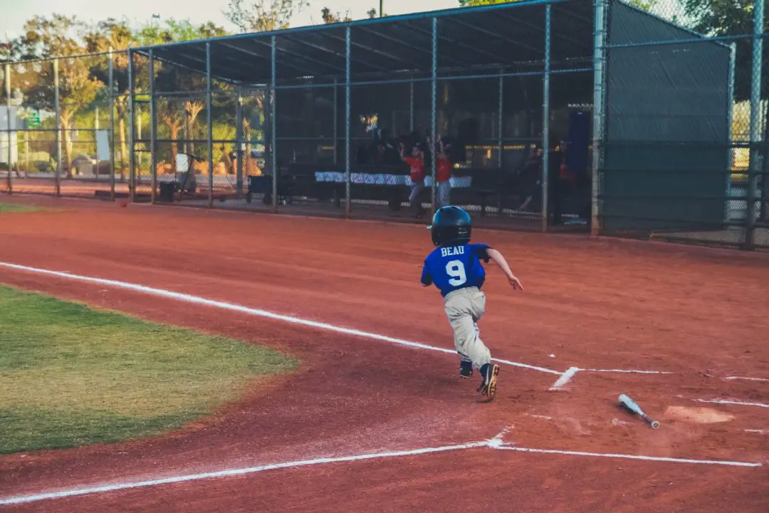 boy running towards first base from home after hitting ball