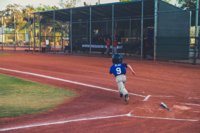 boy running towards first base from home after hitting ball