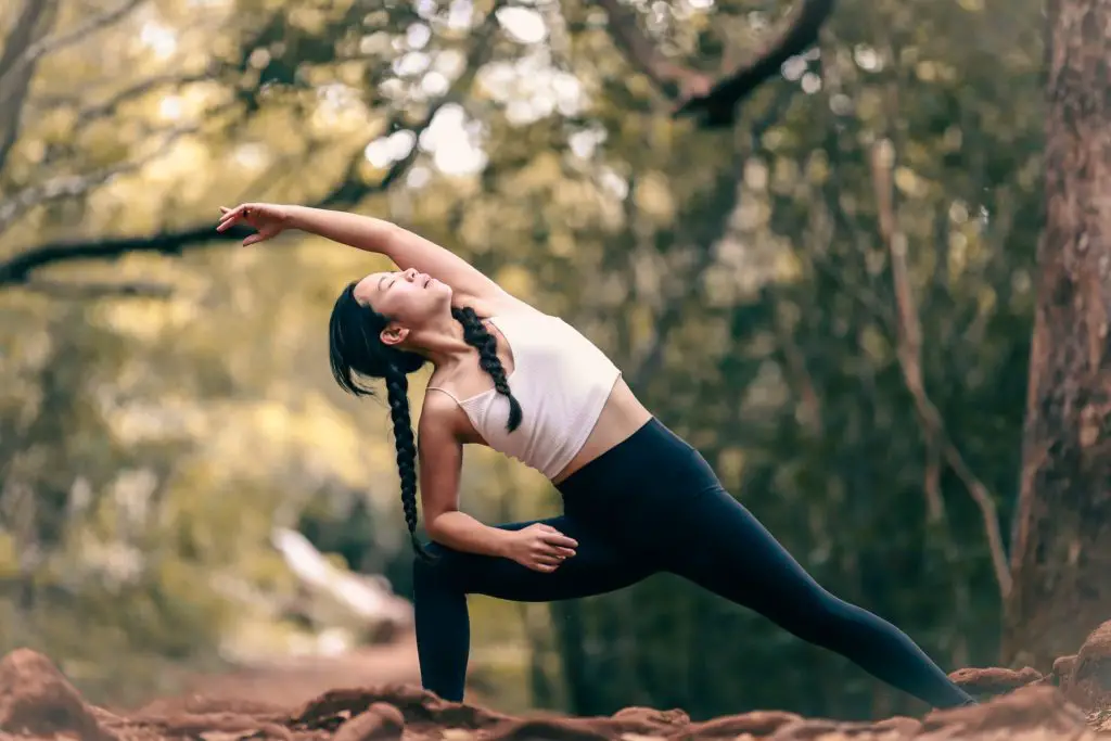 woman doing yoga outdoors in the woods.  Yoga hobby to practice patience