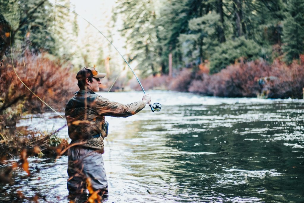 man standing in river fly fishing; fishing hobby to practice patience