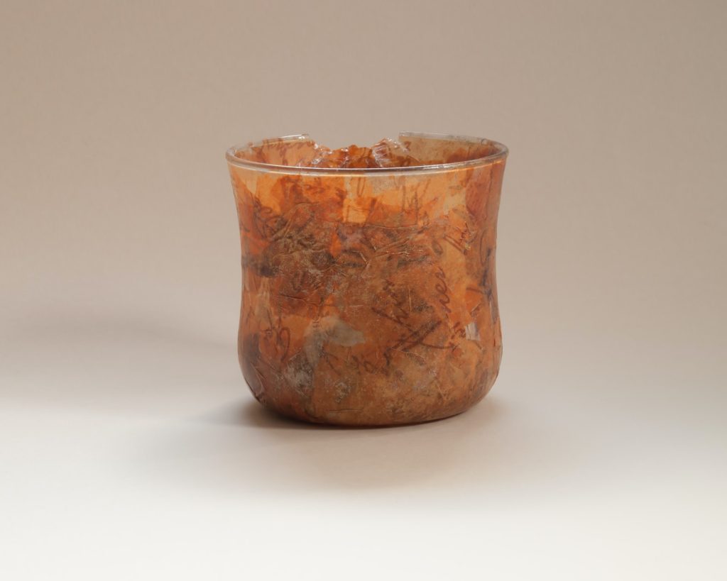 close up of glass jar with decoupage leaves on jar against plain background