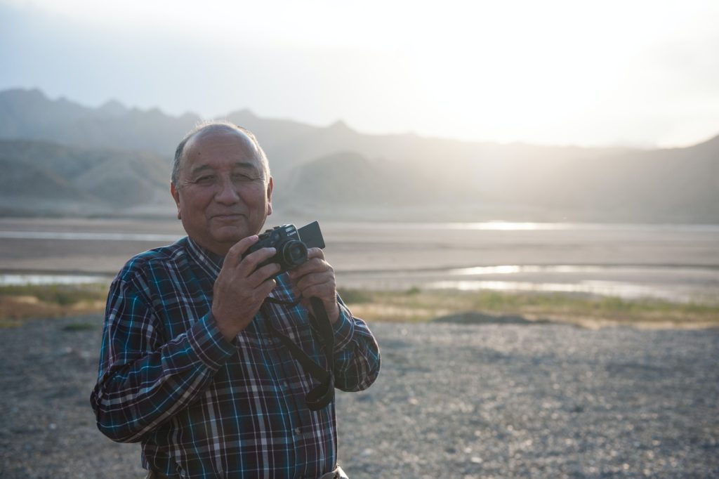 man smiling holding camera outdoors