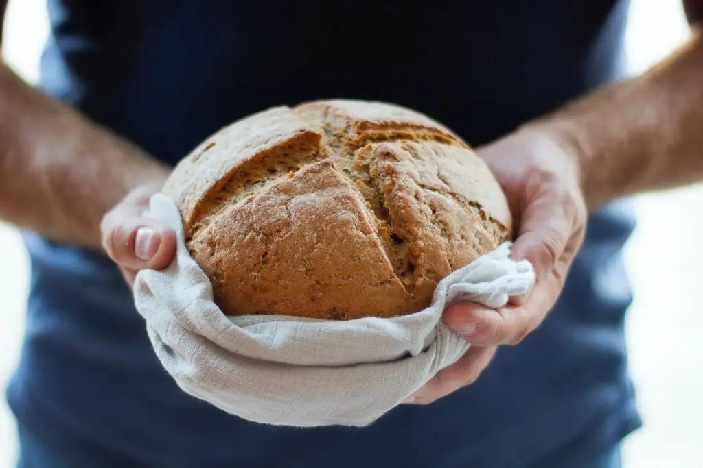 man holding freshly baked bread, bread making food hobby