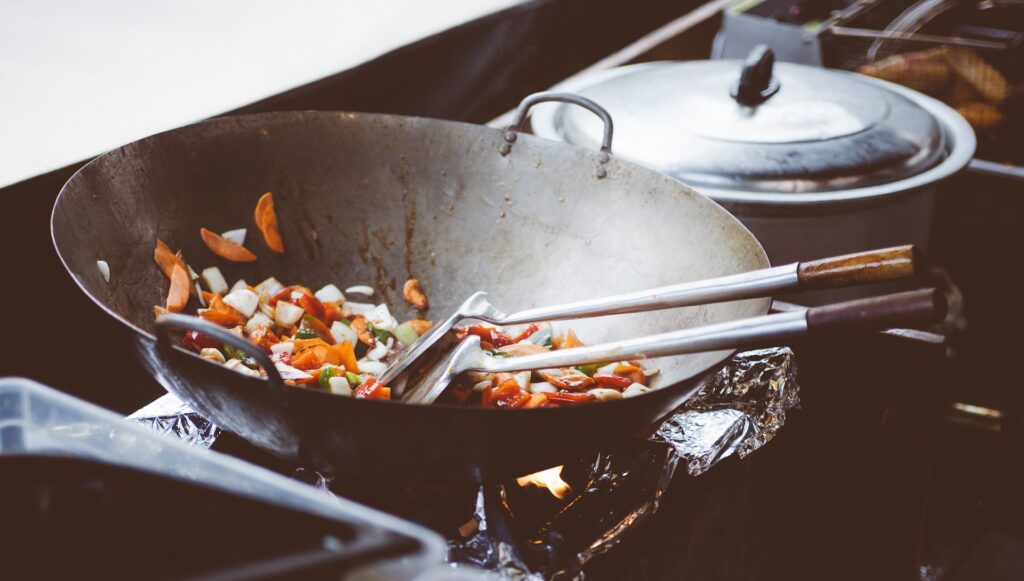 close up of stir fry pot with two spatulas