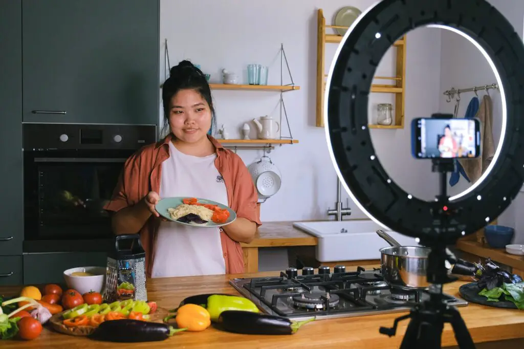 food hobby blog, woman holding dish of food while recording video on cellphone 