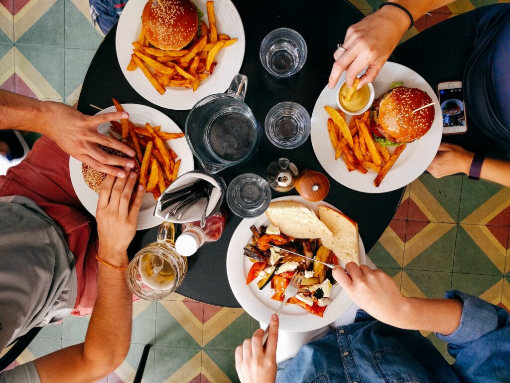 overhead view of friends eating hamburger and french fries, secret shoppers