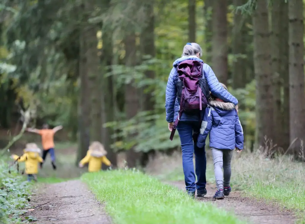 grandmother walking with four children on a forest hike