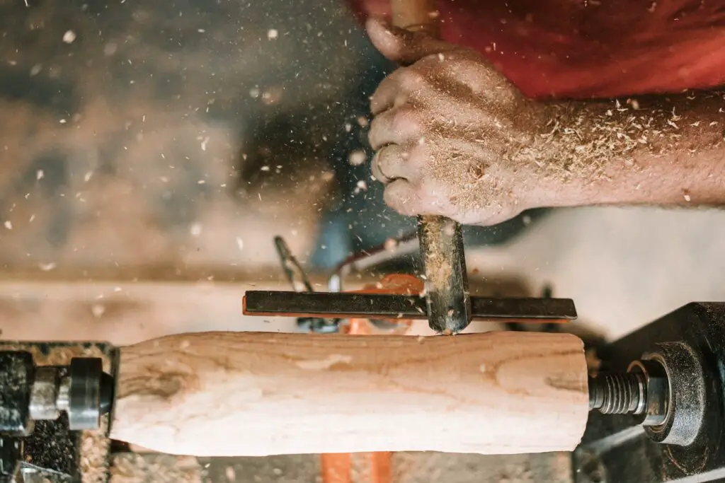 saw dust blowing up as man works on leg of a table; woodworking hobby