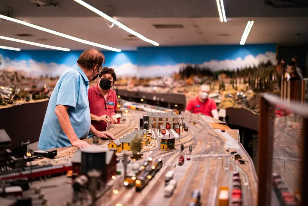 three men working on model trains indoors