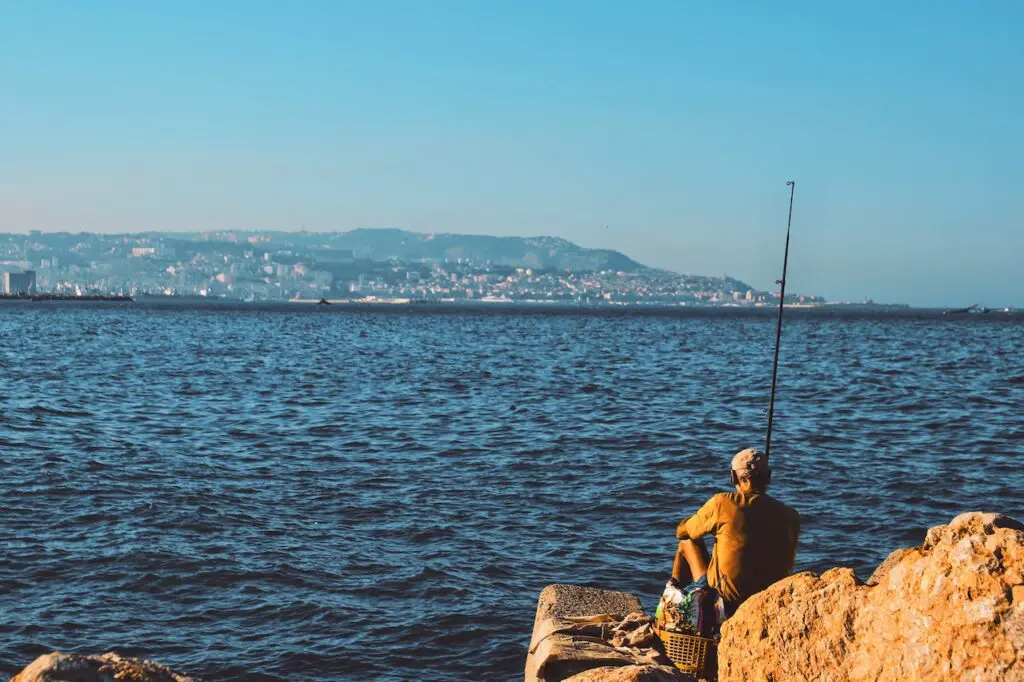 man fishing alone near the ocean on a sunny day