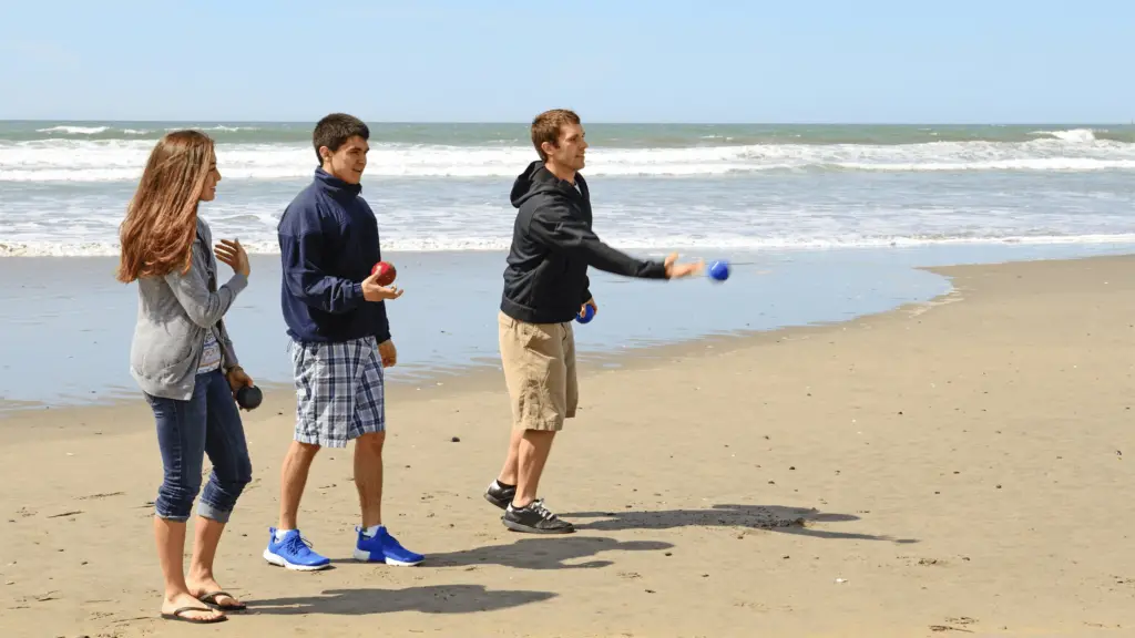 3 people playing bocce ball at a cold beach