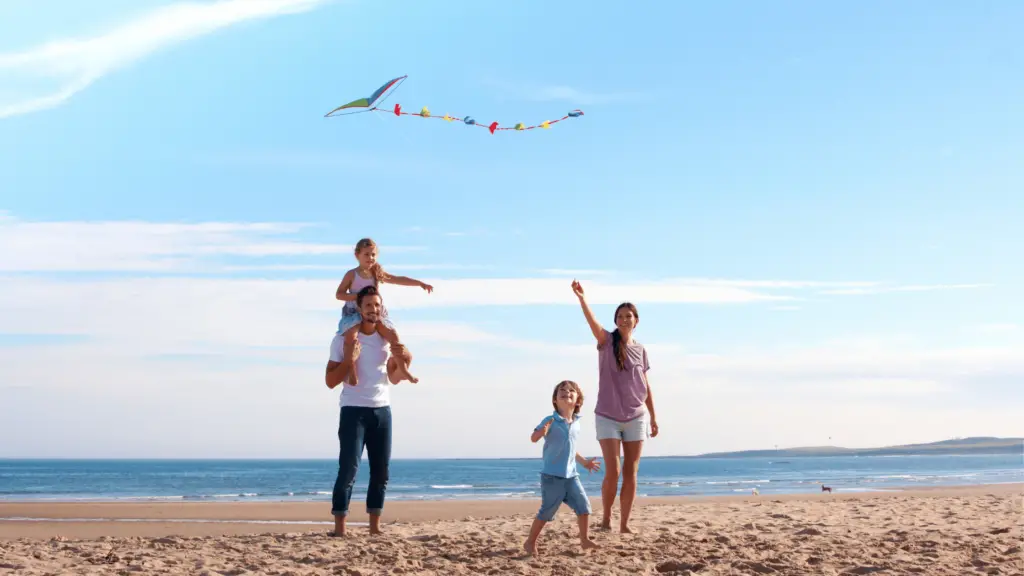 family of 4 flying a kite on the beach