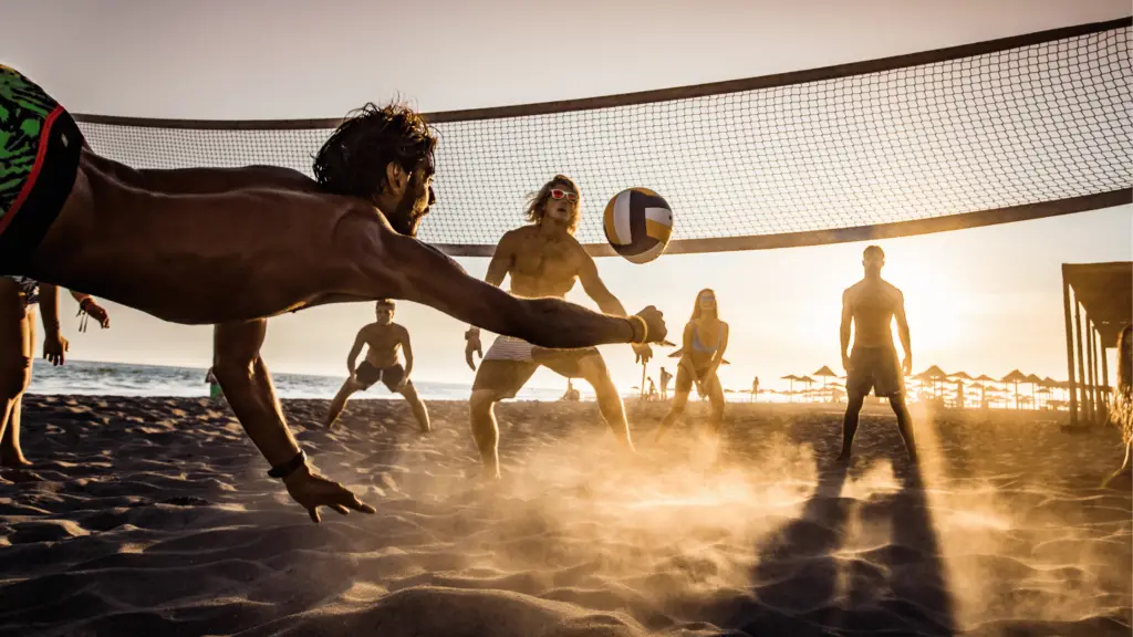 man diving to hit a volleyball on the beach